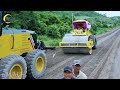 Road construction featuring several large yellow construction machinery, working on a gravel road