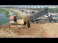 Full landfill project by heavy old bulldozer push dirt into water and 24ton dump trucks loading dirt